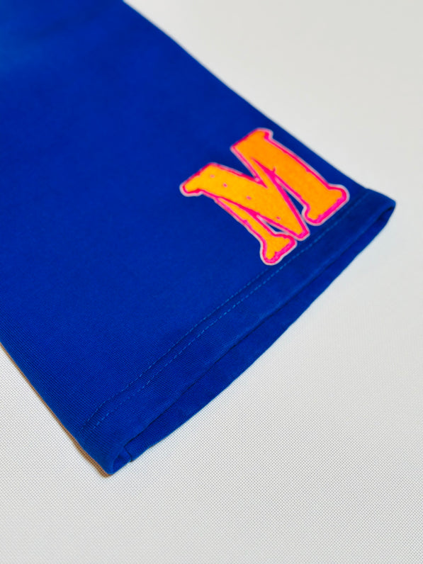 Blue fabric with a large orange letter 'M' bottom left front on a light gray background