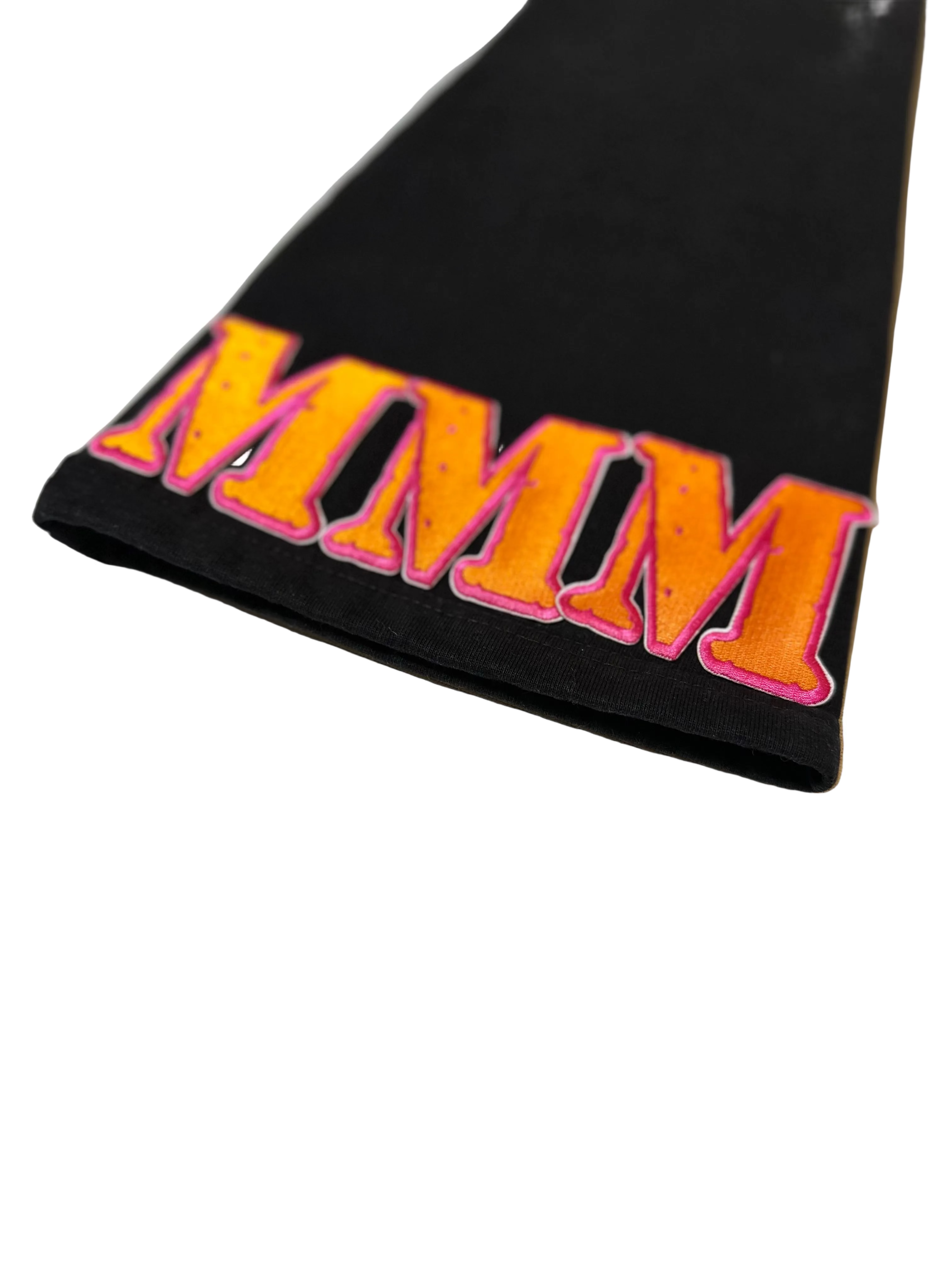 Black fabric with 'MMM' in orange and pink on a white background