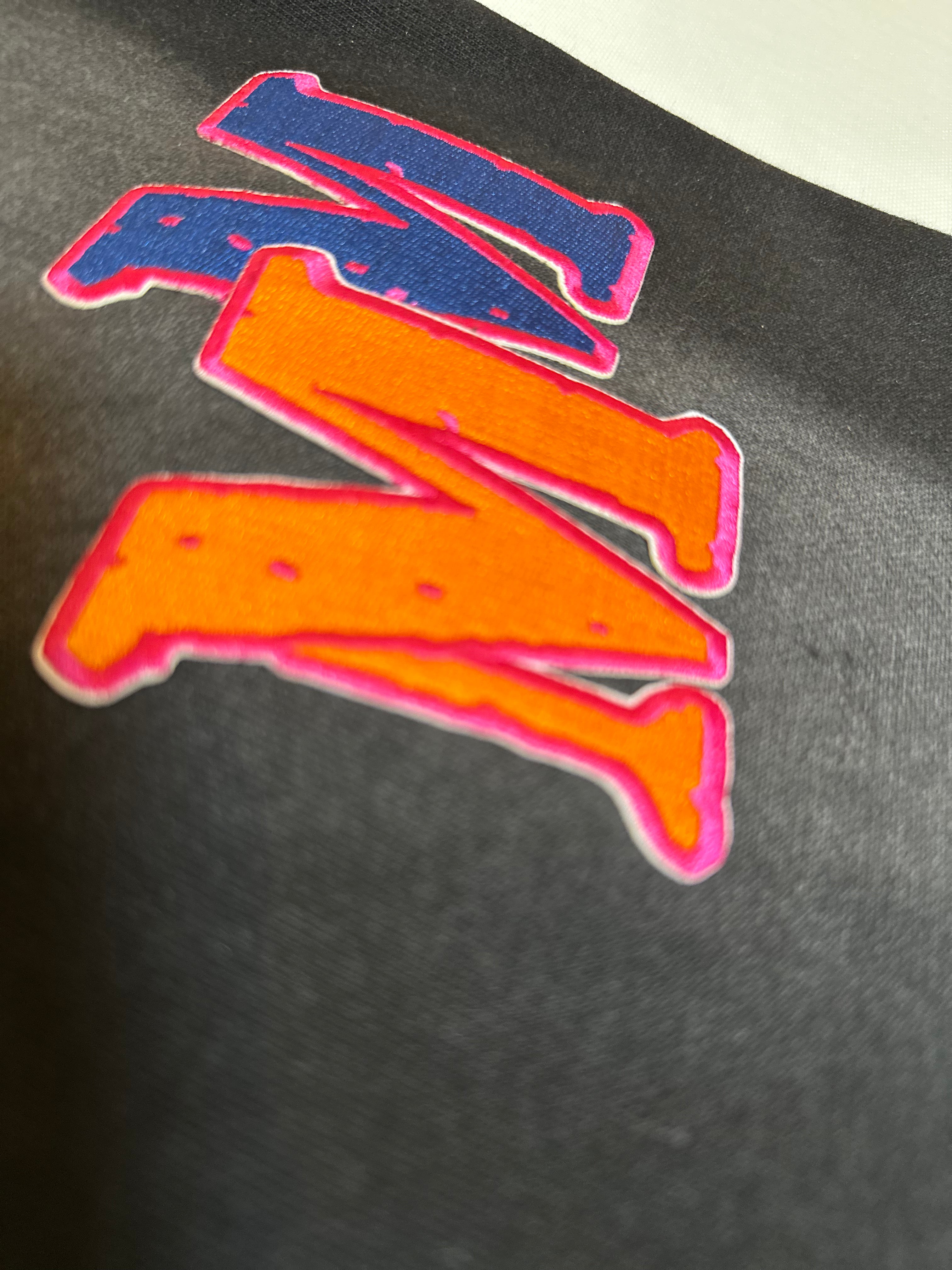 Colorful letter 'M' patch on a black background